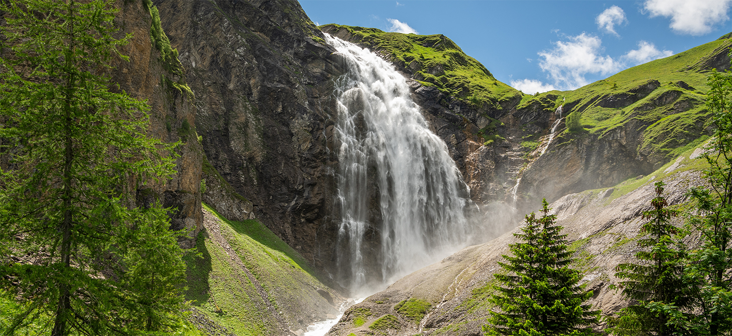 A waterfall surrounded by nature, with water cascading down the rocks.